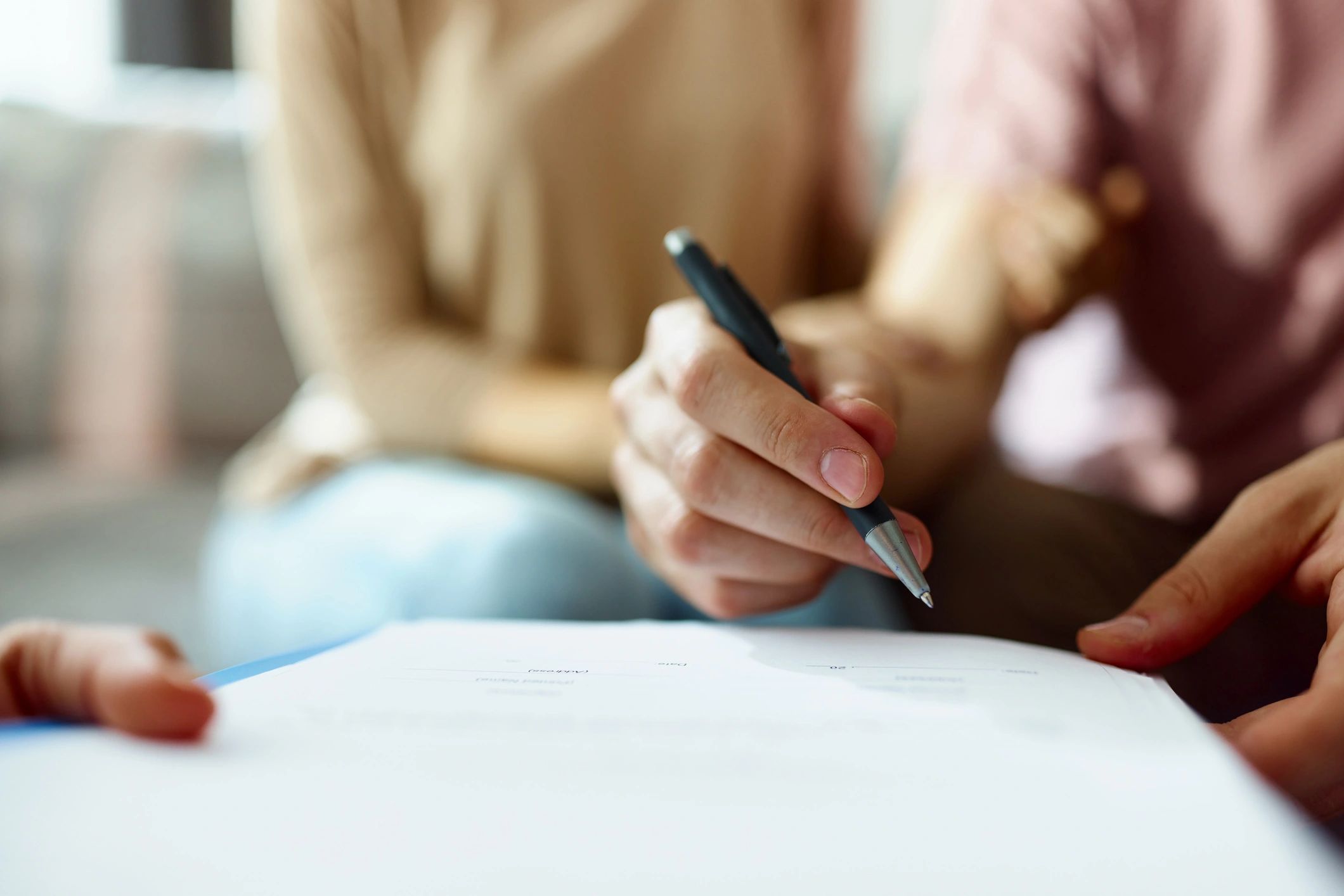 Close-up of a person signing a document with a pen